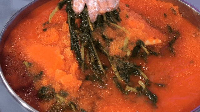 Stirring yeolmu kimchi in a big container with hands