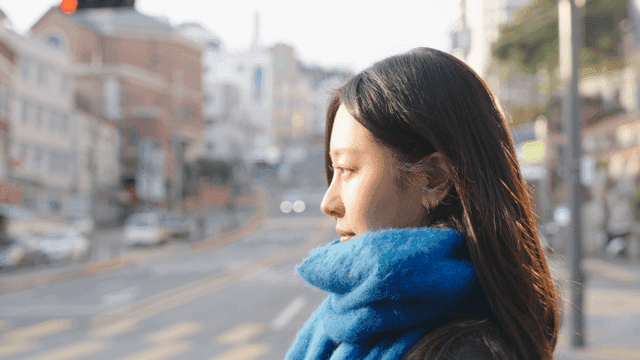 Profile of a woman wearing a blue scarf crossing a crosswalk