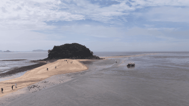 Small island and sandy beach where people walk