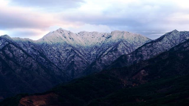 흐린 하늘 아래 광활하게 펼쳐진 눈 덮인 산