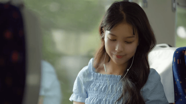 A young woman listening to music on a train