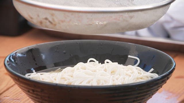 Broth poured over noodles in a black bowl