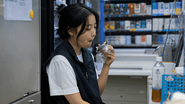 편의점에서 삼각김밥을 먹는 지친 여성 알바
