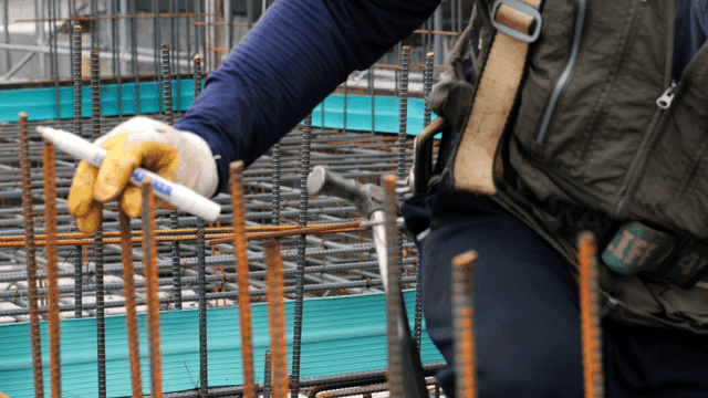 건설 현장에서 철근을 표시하는 작업자