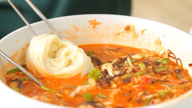 Stirring cold raw fish soup with noodles using chopsticks