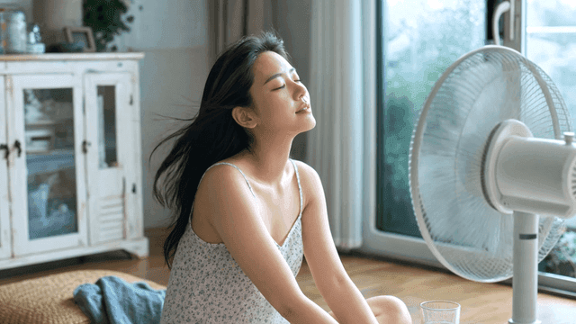 Woman enjoying a cool breeze from a fan