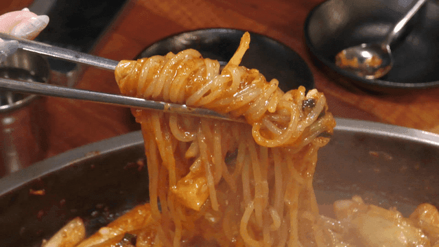 젓가락으로 집은 매운 닭갈비 쫄면