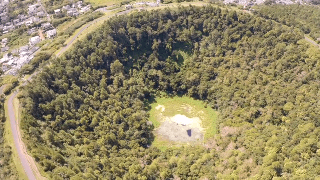 도시 근처 숲이 우거진 분화구의 항공 뷰