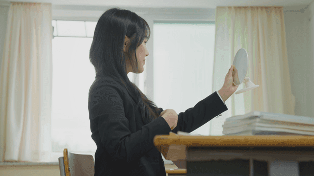 거울로 머리를 확인하는 여학생