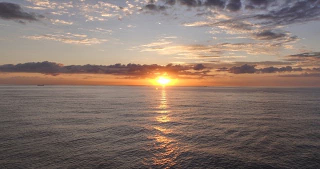 Sunset over a calm ocean with clouds