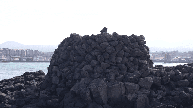 Pile of stones stacked high next to sea