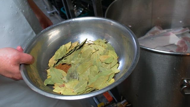 고기가 든 냄비에 월계수 잎과 향신료를 추가하는 모습
