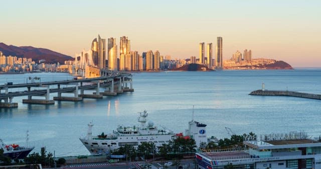 From evening to night view of a bustling port city with tall skyscrapers and bridge