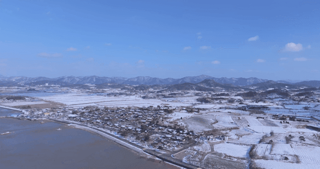 Snow-covered Hanok village and fields with mountains