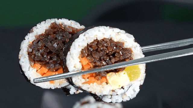 Piece of kimbap picked up with chopsticks