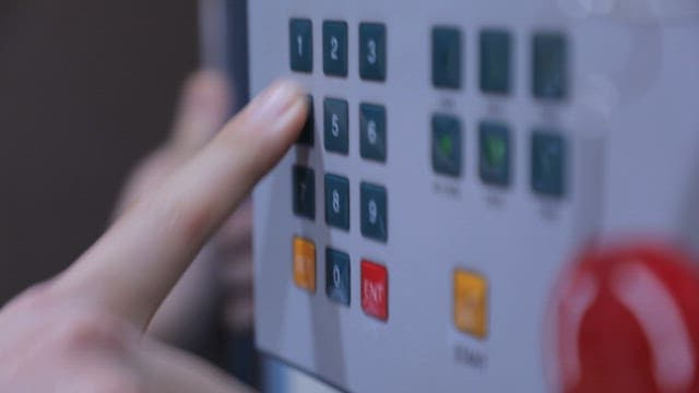 작업자가 산업용 제어판의 버튼을 누르는 모습