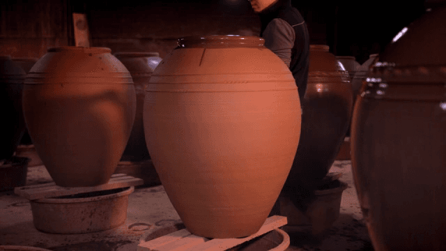 큰 도자기에 붓으로 칠을 하는 사람