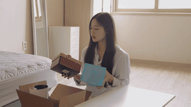 밝은 방에서 상자를 푸는 여성