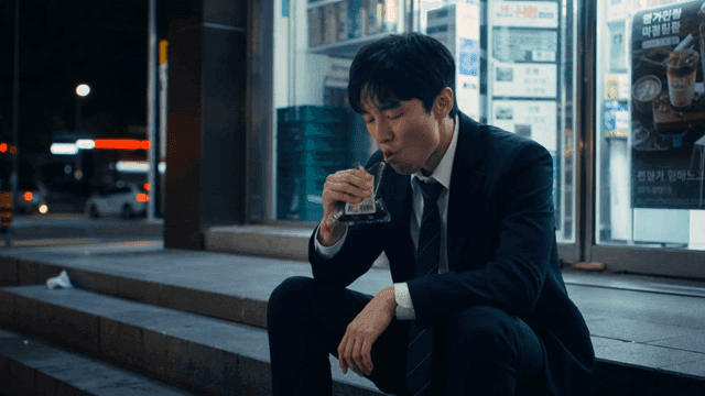 Male office worker eating triangle gimbap outside convenience store