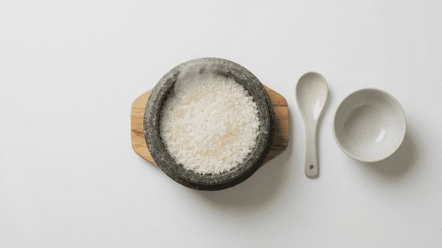 Steaming rice in a stone pot with utensils