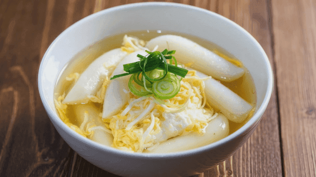 Bowl of garaetteokguk with eggs and green onions