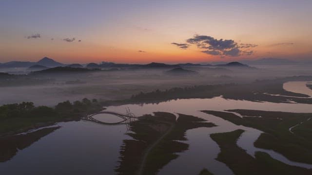 Serene river with misty mountain at sunset