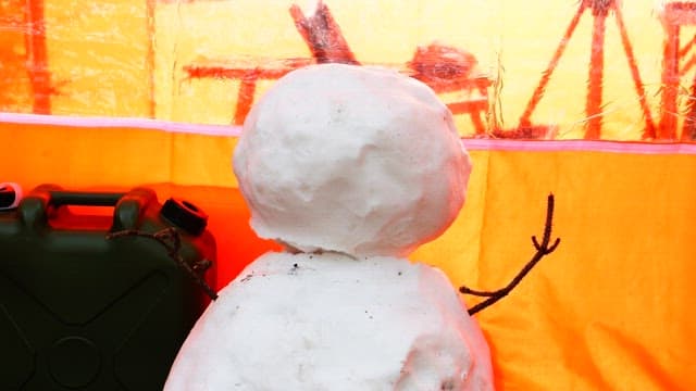 Making a snowman next to an orange tent