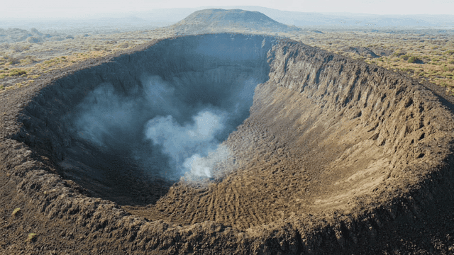 Huge volcanic crater with smoke rising