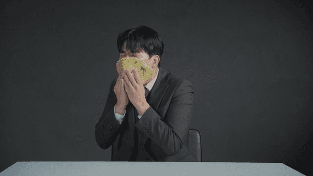 만족스러운 표정으로 돈 냄새를 맡는 남자