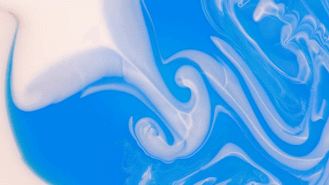 Abstract pattern of blue and white liquids mixing together