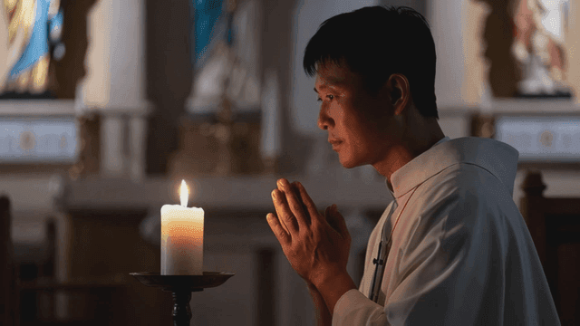 Man praying by candle in cathedral
