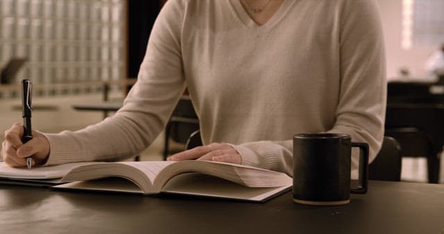 Person Studying in a Quiet Library with Open Book