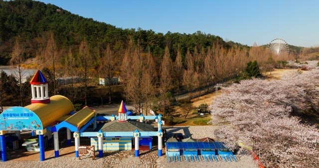 Amusement park surrounded by nature with a ferris wheel next to a lake