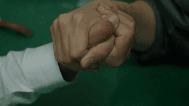 Two people arm wrestling at a table