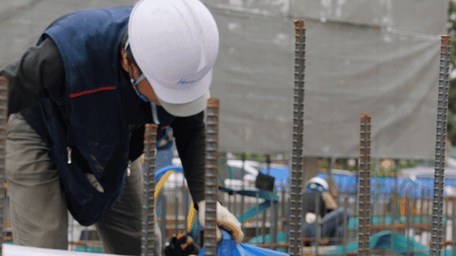 Construction worker putting materials into plastic bag