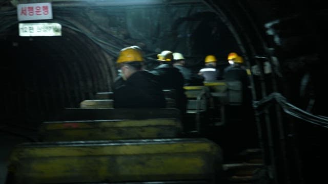 Miners in mine car passing through a dark tunnel of coal mine