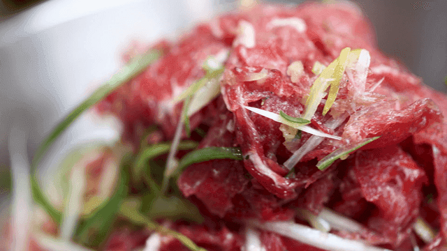 Green onions and seasoned beef bulgogi in bowl