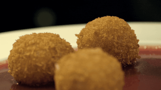 Three croquettes on plate with red sauce