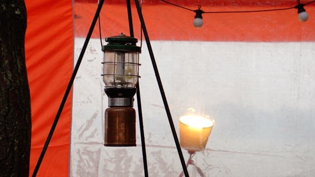 Taking down an unlit camping lantern hanging on a tent