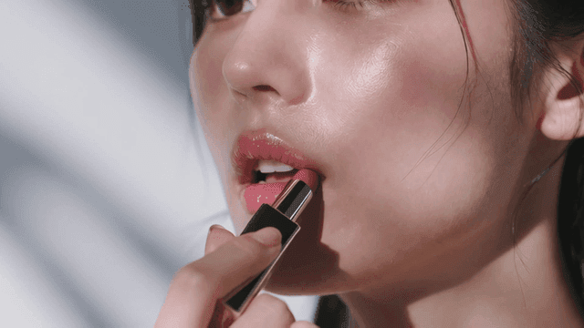 핑크빛 립스틱을 바르는 젊은 여성