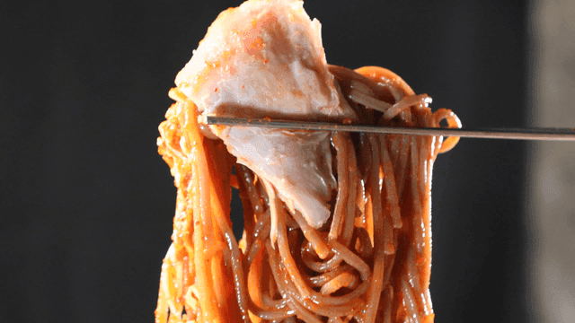 Spicy bibim guksu and chicken picked up with chopsticks