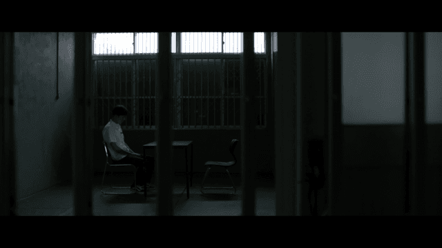 철창이 있는 어두운 방에 홀로 앉아 있는 사람