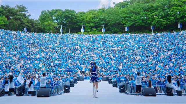 Cheerleader performing in front of a large outdoor crowd