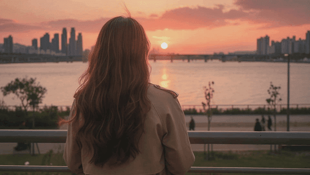 강가에서 일몰을 보는 여성의 뒷모습