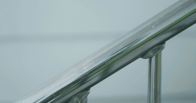 Hand holding a metal railing indoors