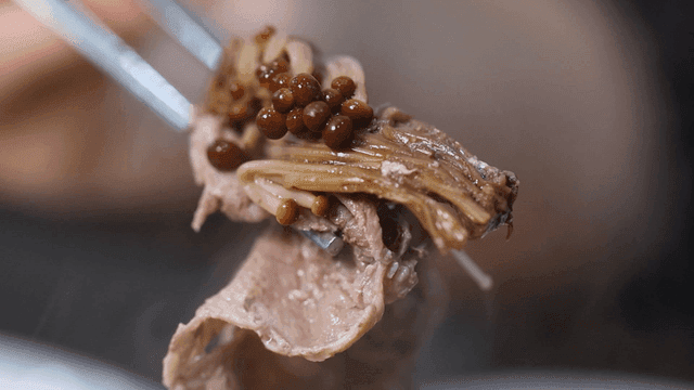 Mushrooms and beef held with chopsticks