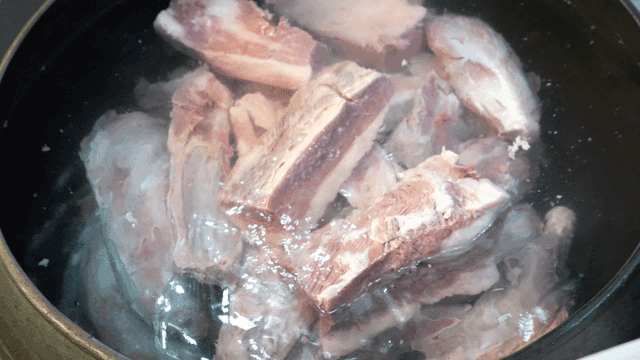 Raw beef cutlets placed in large pot filled with water