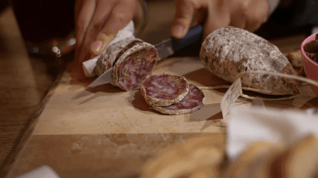 Slicing cured sausage on a wooden board