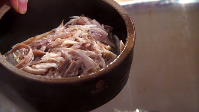 Pouring hot broth over bowl with rice and chicken