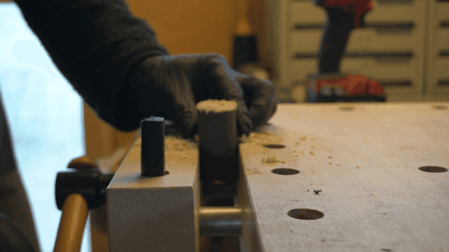 작업장에서 나무 막대를 드릴로 뚫는 공예가